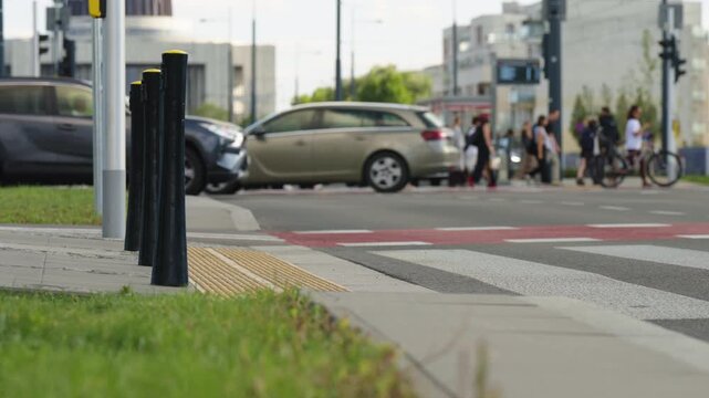 Close up of tactile paving at urban pedestrian crossing with cars moving in background, textured sidewalk surface, crosswalk markings and modern city street infrastructure
