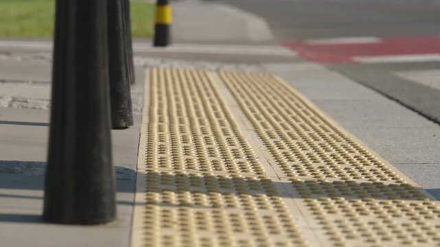 Close up of woman walking across an urban pedestrian crossing, white sneaker stepping on tactile paving, detailed view of female leg and textured sidewalk surface, modern city street daylight