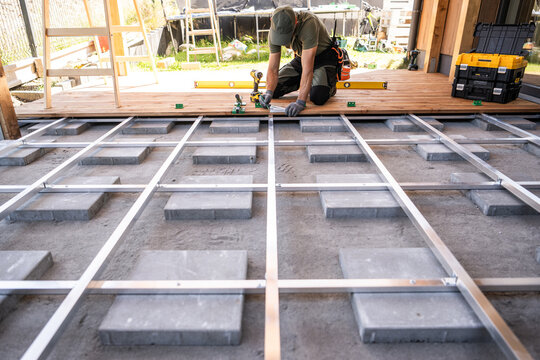 Carpenter measuring wooden decking over a metal subframe