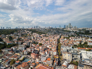 Fototapeta premium Turkey, Istanbul 01 10 2025: Wide drone photo of Ortakoy and Besiktas districts with red rooftop buildings and modern city skyscrapers under a cloudy sky.