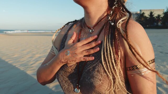 Woman standing with hand over heart on a sunlit beach, practicing mindfulness, embracing spiritual wellness, finding inner peace, and connecting with nature
