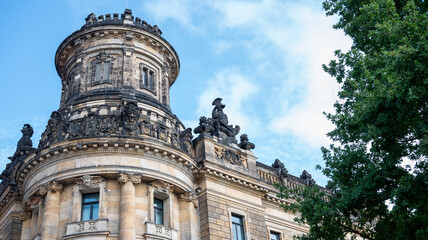 Obraz premium Ornate historic building facade in Dresden, Germany. Detailed stone mascaron sculptures and stained glass windows above arches. Neo-Renaissance architecture heritage