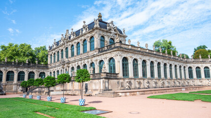 Obraz premium Historic Zwinger Palace in Dresden, Germany. Magnificent baroque architecture with courtyard and green trees under a clear blue sky. Famous landmark and tourism destination