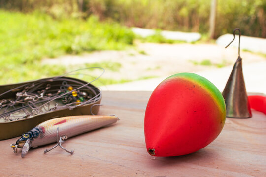 Fishing tackle and equipment for outdoor leisure activities, with a lure, float and hook box on a wooden surface. Outdoor activitys concept