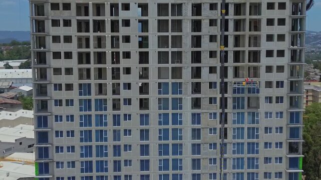 Horizontal panning shot of a modern skyscraper under construction showing unfinished concrete structure and scaffolding.
