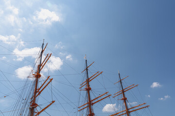 Masts and rigging of the tall ship Kaiwo Maru rise against a blue sky with clouds at Kaiwomaru Park in Toyama, Japan, with copy space. © PH_BRICK