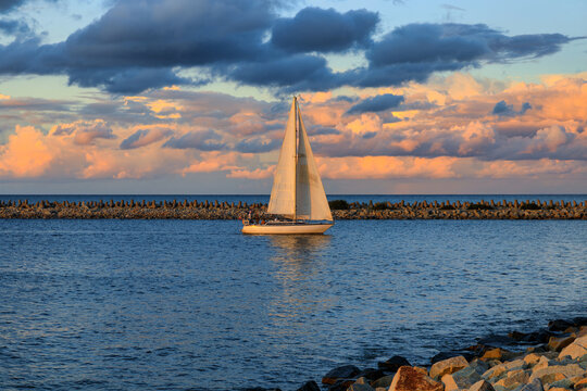 Sailboat entering the port of Gdansk at sunset, Poland.
