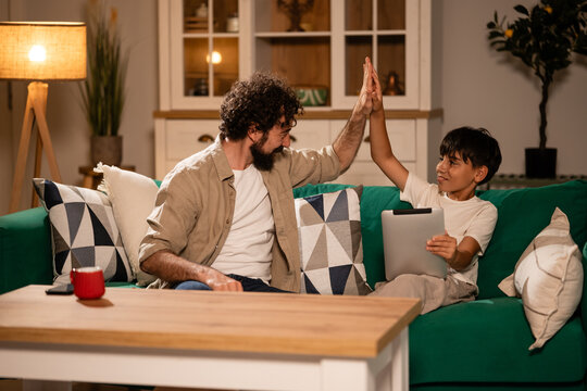Father and son sharing high five and using tablet
