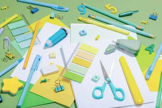 Back-to-school concept, flat lay composition of school supplies on a green background