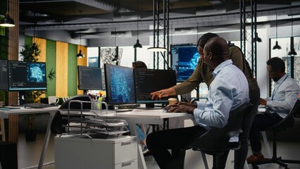 Fototapeta premium AI startup personnel automate workflows with neural networks on a PC while a team leader and colleague refine deep learning models for faster processing.