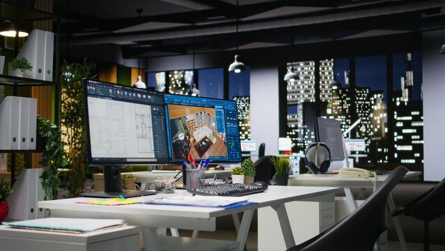 Empty design office features a modern desk with blueprint drafting and 3D modeling software on screen, emphasizing digital creative visualization.