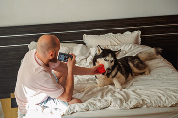 Man photographing his husky with a red ball in his hand © iwavephoto