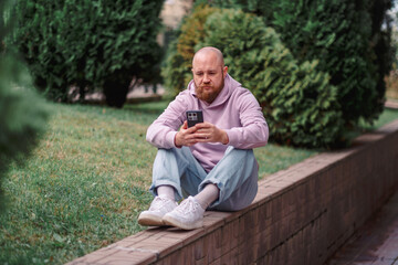 Fototapeta premium Man typing a message on his phone outdoors on a lawn