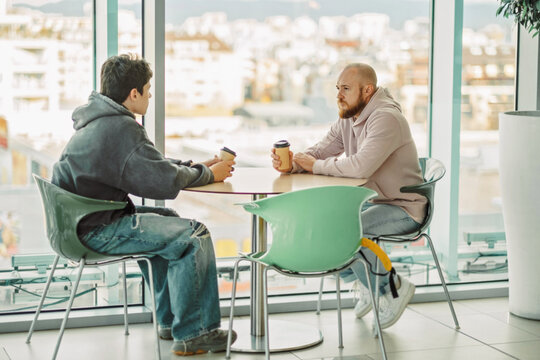 Man and teenage boy at a table by a panoramic window