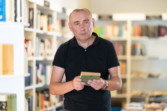 Adult male reader explores aisles of bookstore, looking for new title to enjoy