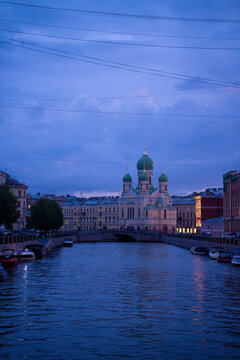 Classic historic orthodox church cathedral building facade near urban river canal at twilight blue hour.
