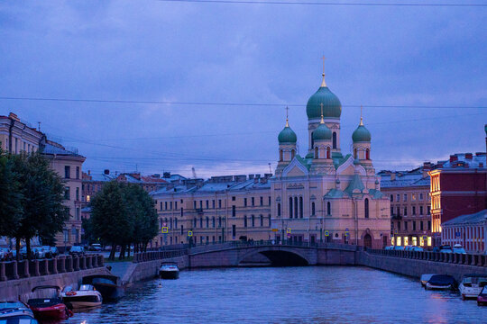 Classic historic orthodox church cathedral building facade near urban river canal at twilight blue hour.
