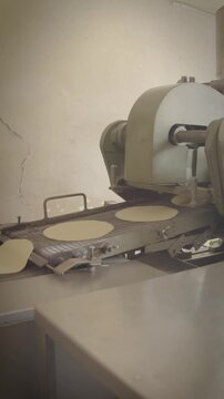 Tortilla machine feeding tortilla dough onto conveyor belt
