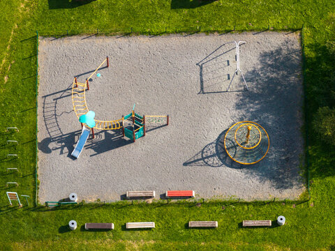 Aerial view of the playground at Traku Vokes papludimys featuring climbing frames, a slide, and a circular climbing net surrounded by grass and benches in Vilnius, Vilnius County, Lithuania.
