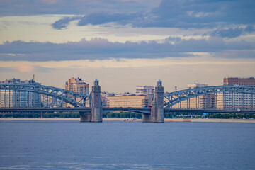Obraz premium Historic metal arch bridge with stone towers over wide city river panorama. 