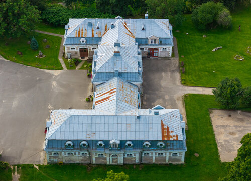 Aerial view of Traku Voke Manor featuring a historic U-shaped building with a weathered metal roof, surrounded by green lawns and paved paths in Vilnius, Vilniaus apskritis, Lithuania.