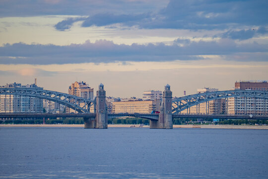 Historic metal arch bridge with stone towers over wide city river panorama.
