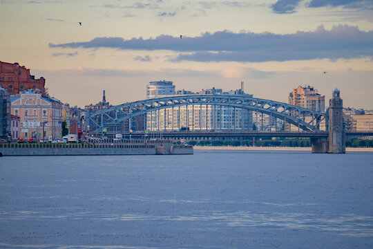 Historic metal arch bridge with stone towers over wide city river panorama.

