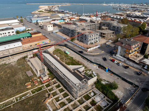 Aerial view of the construction site at the former Ex Stadio Fratelli Ballarin with a red tower crane and concrete structures in San Benedetto del Tronto, Marche, Italy.