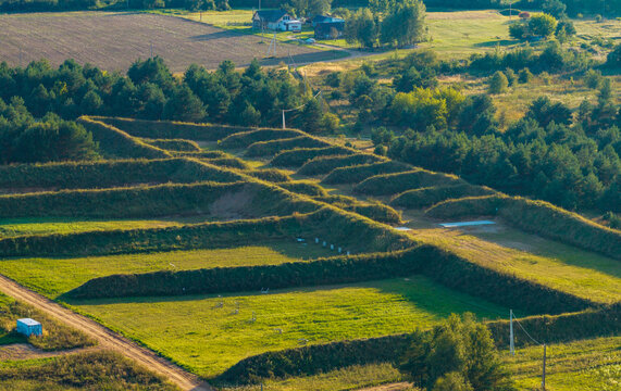 Aerial view of a shooting range with earthen berms and grass fields surrounded by forest in Ciobiskis, Vilnius County, Lithuania.
