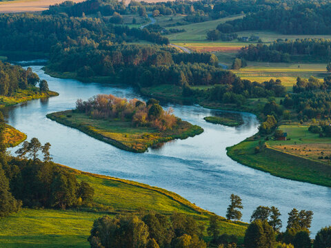 Aerial view of the Neris River winding through the lush green landscape of the Kernave Archaeological Site in Kernave, Vilnius County, Lithuania.