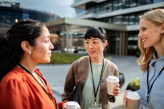 Women professionals networking during coffee break outside office