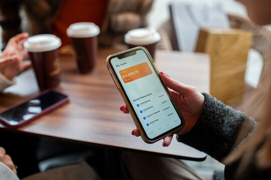 Person checking mobile banking app at coffee shop table