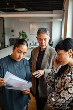 Three colleagues reviewing documents in a modern office