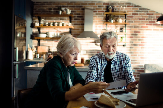 Senior couple managing household finances at home kitchen table
