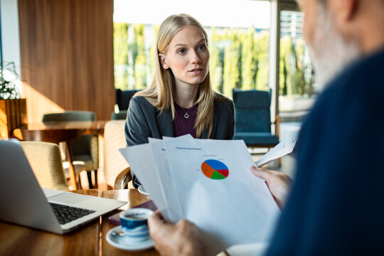 Businesswoman consulting client over financial report in cafe