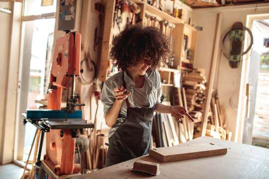 Woman woodworker crafting at a workbench in a home workshop