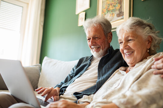 Happy senior couple using laptop at home