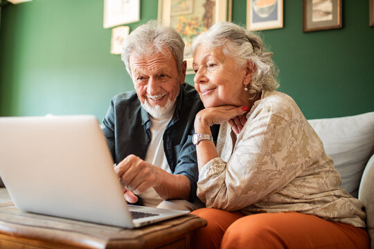 Smiling senior couple using laptop at home