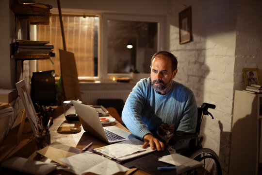 Man in wheelchair working late at home office