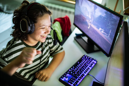Smiling child playing pc video game at home