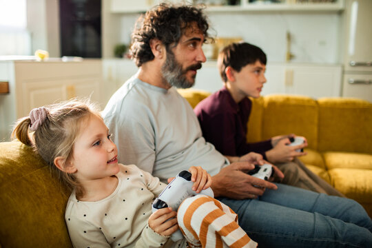 Father and children playing video games at home