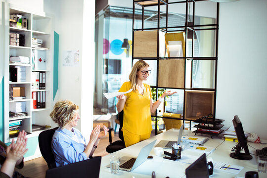 Businesswomen applauding colleague during presentation in modern office