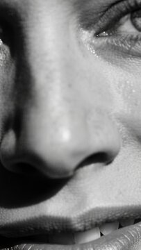 Vertical video: Showing woman reacting to studio light, tensing lip and parting lips, tear glinting