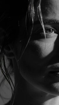 Vertical video: Reacting woman shifting head to key studio light, eye cheek lips wet hair moving
