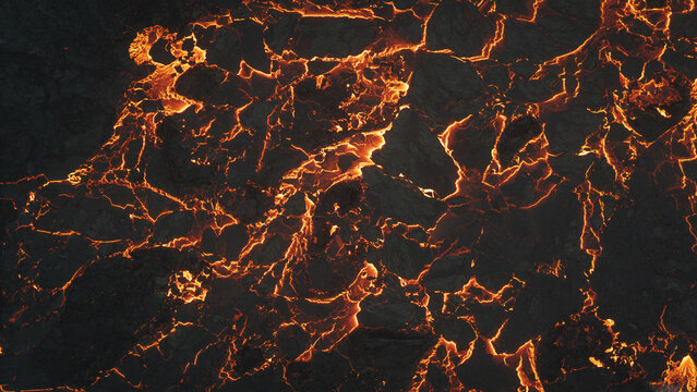 Aerial view of glowing molten lava flowing through dark volcanic rock fissures, creating a dramatic contrast of heat and cooling crust in Reykjavik, Reykjavikurborg, Iceland.