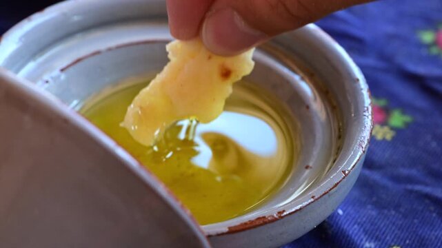 Marrakech, morocco. August 9, 2026. Slow motion close up of a person dipping a piece of fresh moroccan bread into a bowl of extra virgin olive oil. Traditional appetizer