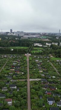 Beautiful aerial drone video of Kumpula Allotment Gardens in Helsinki, Finland, surrounded by lush green vegetation, garden plots, small cottages, and peaceful summer scenery.
