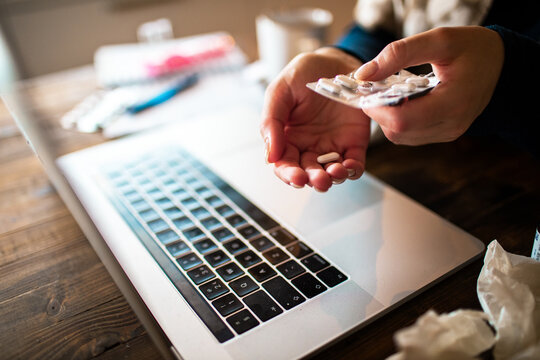 Sick person taking pills at home office desk