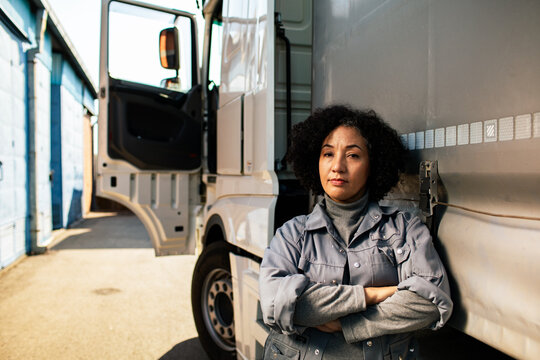Confident woman truck driver standing by semi at depot