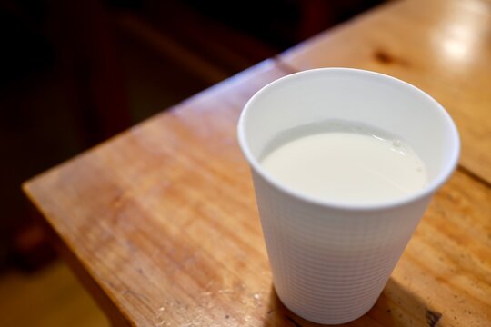 四国カルスト産牛乳。白いカップに入った新鮮な牛乳。コピースペースあり